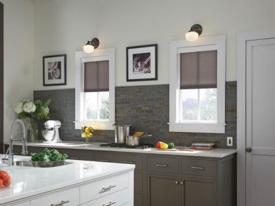 A kitchen with two windows with charcoal shades half opened.